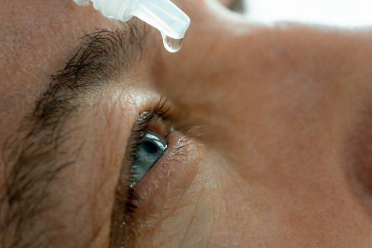 A man puts eye drops in his eyes.