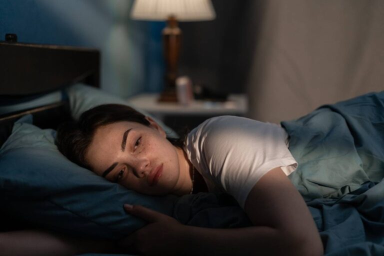 Young woman lying in bed late at night trying to sleep suffering insomnia.